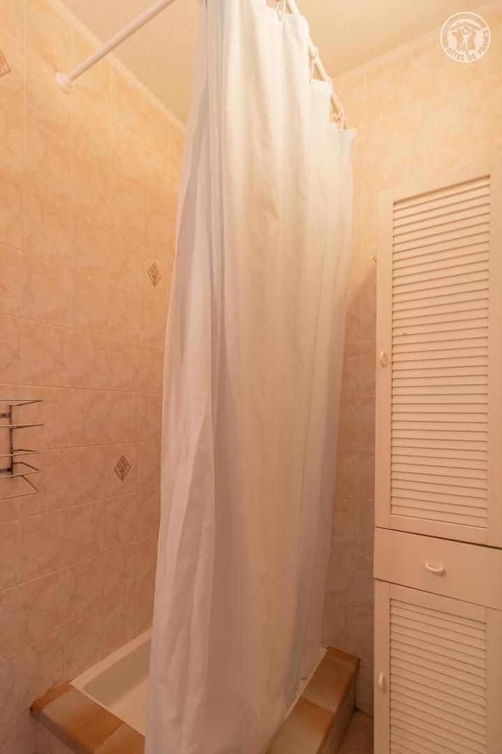 Un baño con cortina de ducha, bañera y un armario de madera.