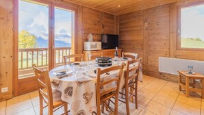 A wooden cabin with a dining area, a television, and a view of the outdoors. - O'mikely - LE Dingo - Albiez Montrond (ALBIEZ MONTROND)