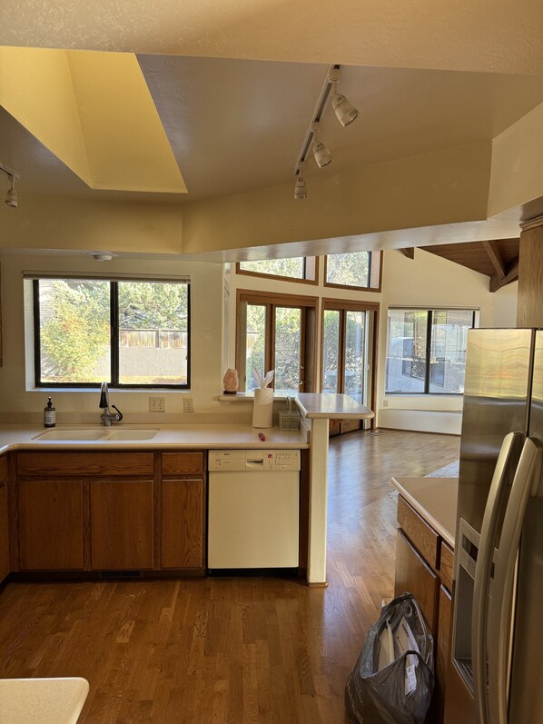 A modern kitchen with wooden cabinets, a Bosch dishwasher, and a stainless steel refrigerator.