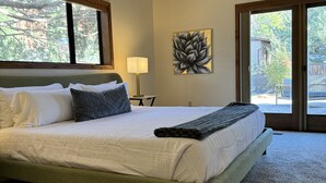 Ein Schlafzimmer mit einem großen Bett, einem Deckenventilator, einem Fenster und einer Tür, die auf einen Balkon führt.