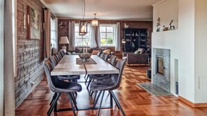 A spacious dining area with a long wooden table, leather chairs, and a fireplace. - 7 bedroom awesome home in Tjørhom (Tjørhom)