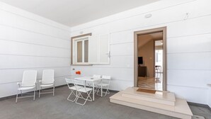 Une pièce moderne et minimaliste avec des murs blancs, un sol carrelé et un petit coin repas comprenant une table et des chaises.