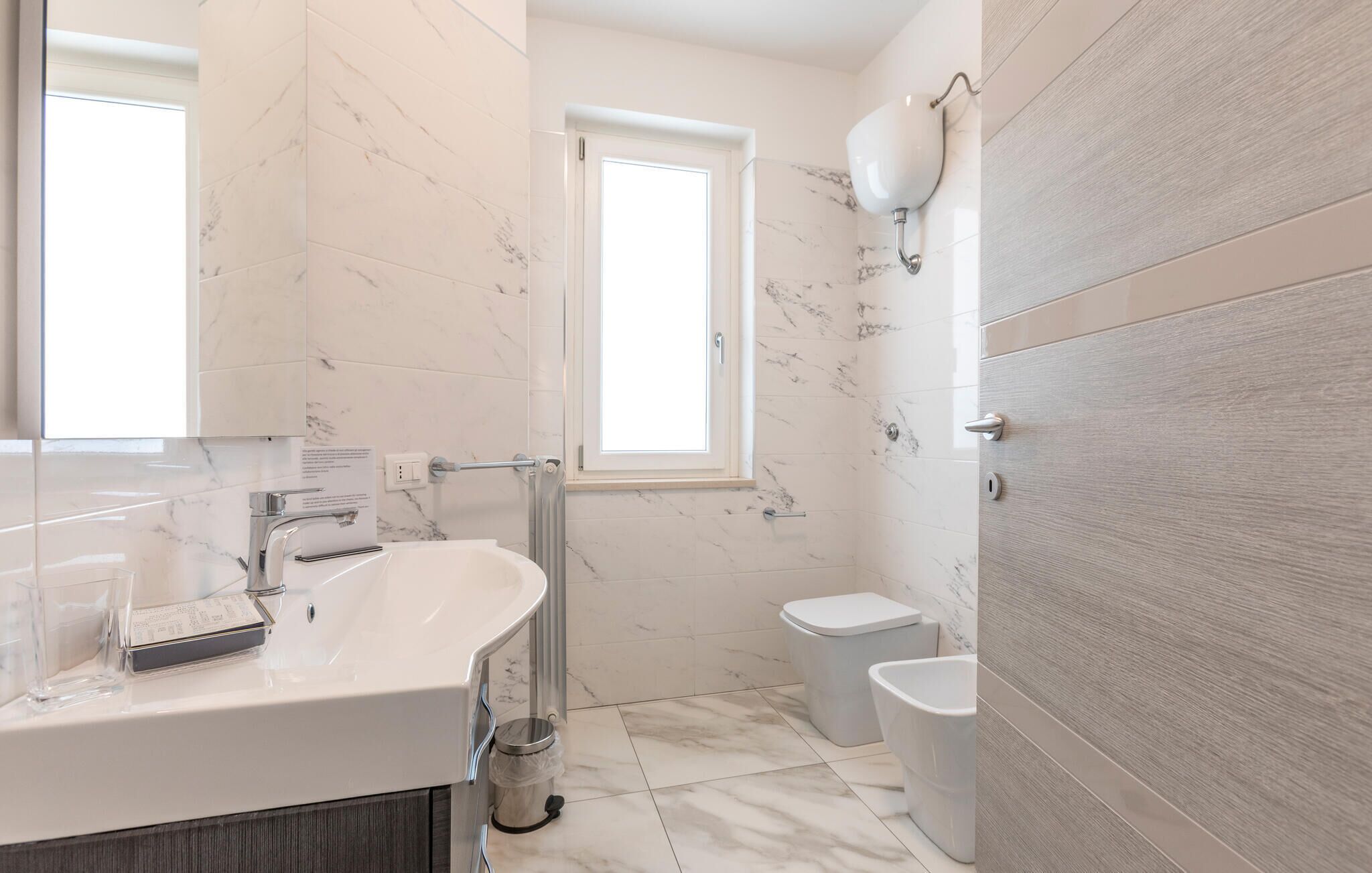 Une salle de bain moderne avec un lavabo en marbre, des toilettes et un espace douche.