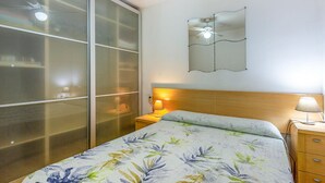 A bedroom with a bed, a nightstand, a mirror, and a sliding glass door. - 2 bedroom beautiful apartment in Benidorm (Benidorm)