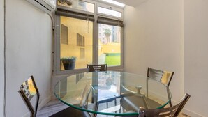 A glass-top table with four chairs in a room with a window overlooking a building and a green area. - 2 bedroom beautiful apartment in Benidorm (Benidorm)