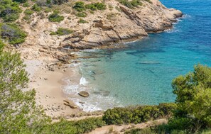 Paisatge costaner amb penya-segats rocosos, mar blau clar i vegetació escassa.