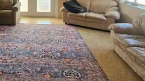 A living room with a beige sofa, a patterned rug, and a ceiling fan. - Beach House with Pool (Englewood)