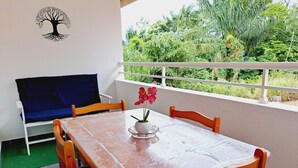 Ein Balkon mit Tisch, Stühlen und einem blauen Sofa.