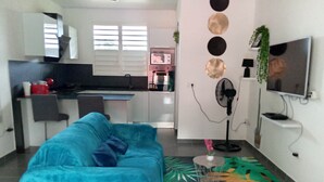 Ein Wohnzimmer mit einem blauen Sofa, einem Fernseher und einem Ventilator.