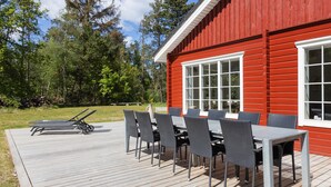 A red wooden building with a deck and outdoor seating area.
