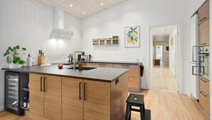 A modern kitchen with wooden cabinets, a central island, and a wine fridge.