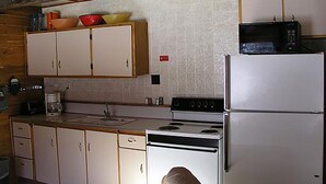 A kitchen with white cabinets, a stove, a microwave, and a refrigerator. - High Mountain 3 BR log home w/ fireplace (Lake City)
