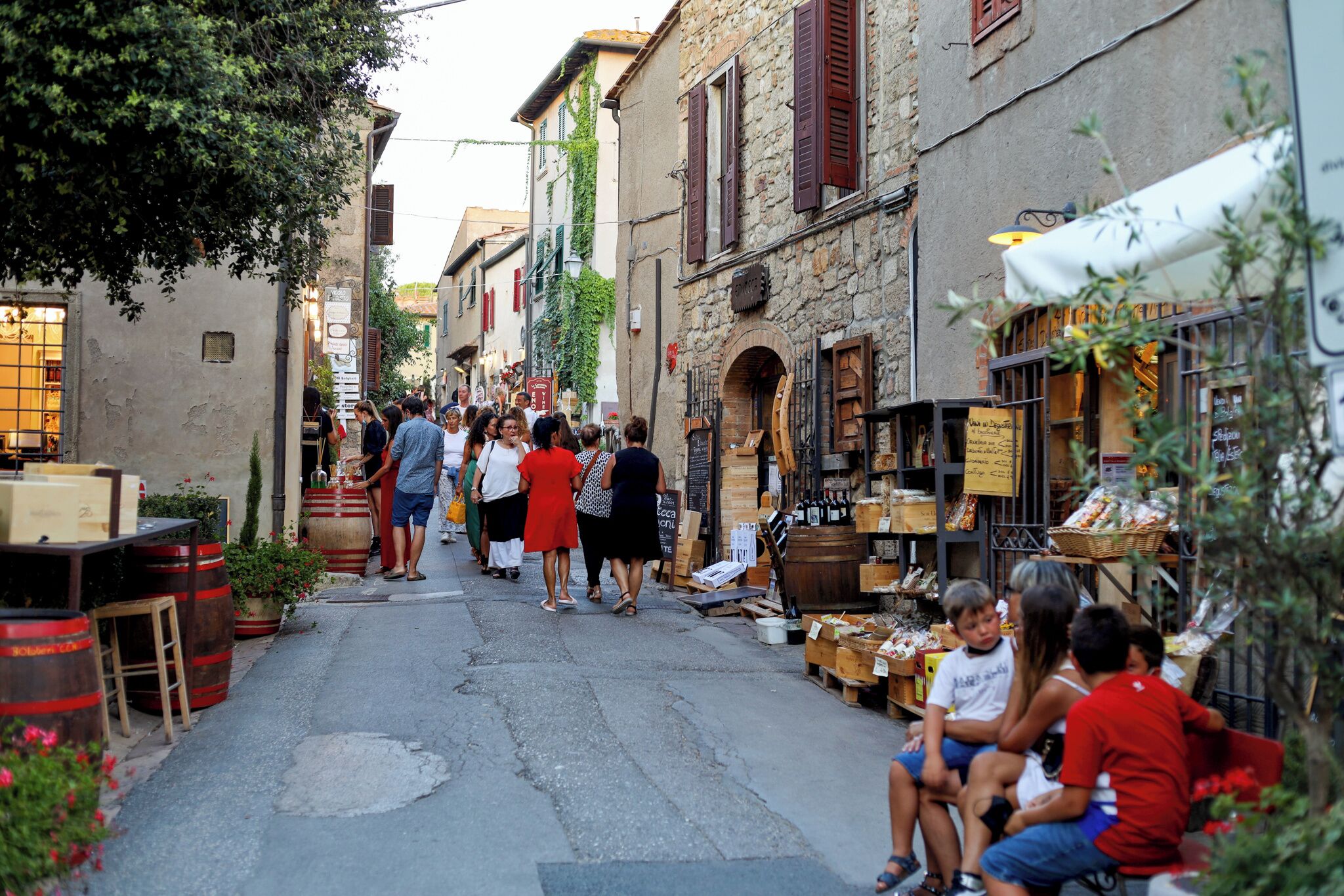 A narrow street with shops and people walking.