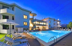 A modern hotel with a swimming pool, lounge chairs, and a well-lit outdoor area. - Studio with air conditioning (Cecina)