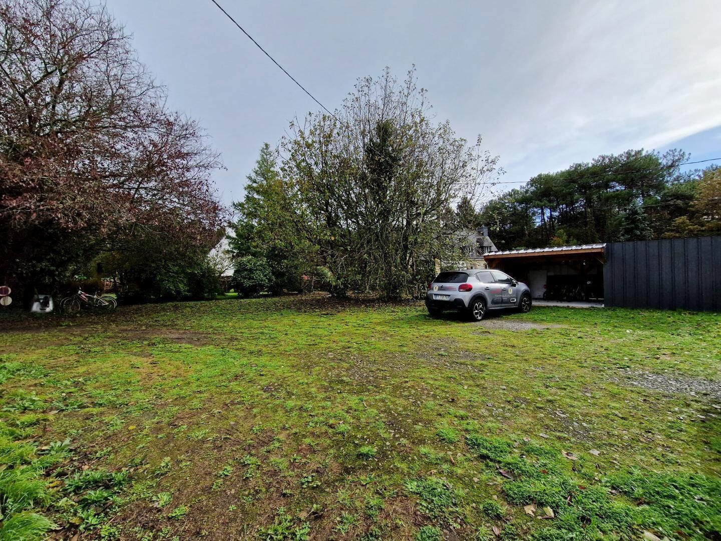A residential area with a parked car, a garage, and a grassy yard.