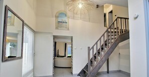 Ein geräumiger Flur mit einer Holztreppe, einem großen Spiegel und einer Deckenleuchte.