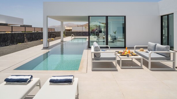 A modern outdoor pool area with lounge chairs and a dining table. - AVASARALA by Buenavilla | A 3 bedroom luxury villa in Puerto Calero (Puerto Calero)
