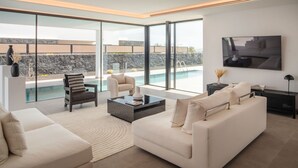 A modern living room with a large window, a pool, and a minimalist design. - AVASARALA by Buenavilla | A 3 bedroom luxury villa in Puerto Calero (Puerto Calero)