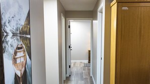 Un couloir avec un plancher en bois, une table à manger avec des chaises et un buffet en bois.