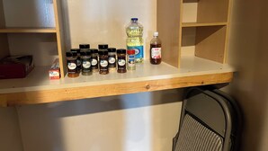 Una repisa de cocina con diversas especias y condimentos, incluyendo una botella de vinagre de manzana y una botella de aceite de oliva.