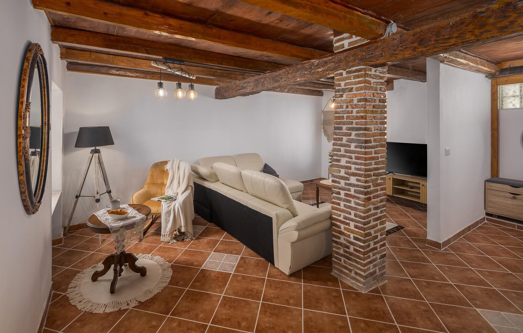 A living room with a sofa, a TV, a lamp, and a brick pillar.