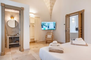 A hotel room with a bed, a television, a bathroom with a sink, and a chair.