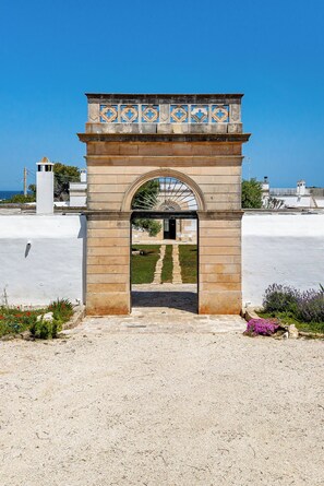 A stone archway with a decorative top, leading to a pathway. - masseria gorgognolo (Ostuni)