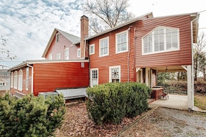 Ein zweistöckiges Haus mit roter Fassade, einer Veranda und einem kleinen Garten.