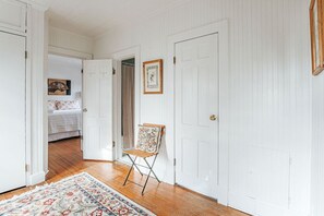 Un couloir avec des portes blanches, un tapis à motifs et une chaise.