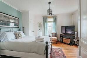 Una camera da letto con un letto, una televisione, una sedia e uno specchio.