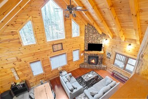 Ein gemütliches Blockhaus mit Kamin aus Stein, Holzwänden und großen Fenstern.