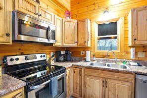 A kitchen with wooden cabinets, a stainless steel stove, a microwave, and a granite countertop.