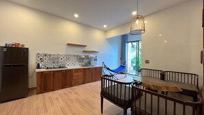 A modern kitchen with a built-in refrigerator, wooden cabinets, a tiled backsplash, and a dining area with a table and chairs. - Nhu House Apartment Phu Quoc  (Phu Quoc)