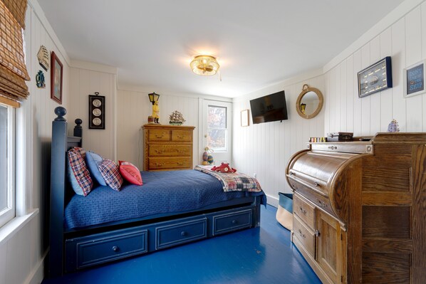 Ein Schlafzimmer mit einem Bett, einem Schminktisch und einem Fernseher an der Wand.