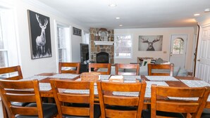 A dining room with a stone fireplace, wooden chairs, and a table set for six. - Spacious Chalet - PetFriendly/HotTub/Firepit/GameRoom/AC (Wilmington)