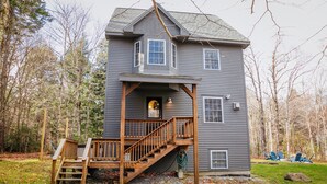 A two-story house with a wooden deck and stairs leading to a front door. - Spacious Chalet - PetFriendly/HotTub/Firepit/GameRoom/AC (Wilmington)