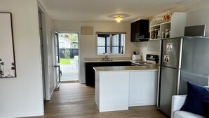 Eine moderne Küche mit einer zentralen Kochinsel, einem Essbereich mit einer Couch und Blick auf den Garten.