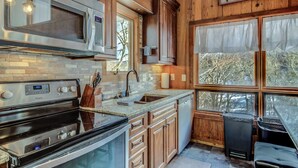 A kitchen with wooden cabinets, a stainless steel microwave, a double oven, and a sink.