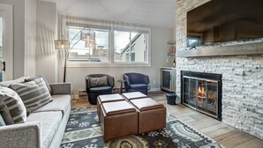 A modern living room with a fireplace, a sofa, a chair, and a rug.