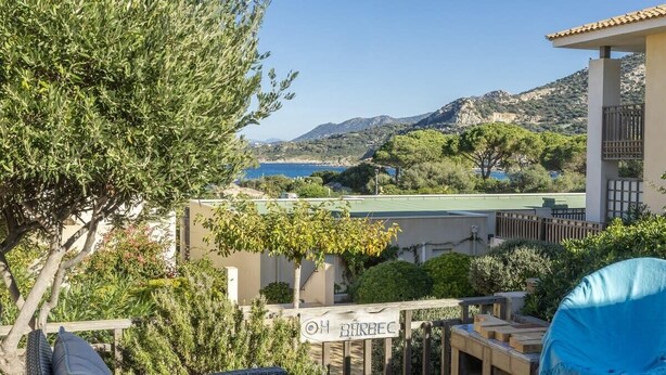 A terrace with wicker furniture, a sign reading "OH BARBEC", and a view of the sea and hills. - Casa Azul Turquesa (Lumio)