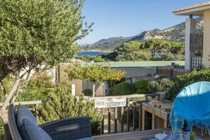 A terrace with outdoor seating, a sign reading 'OH BARBEC,' and a view of the sea and hills. - Casa Azul Turquesa (Lumio)
