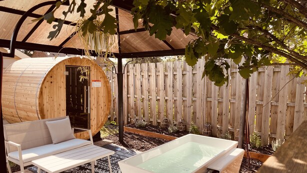 Un área de spa con un jacuzzi, una sauna de madera y una zona de estar cubierta con un tapete estampado.