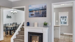 Un salon moderne avec une cheminée, un coin repas et un escalier.