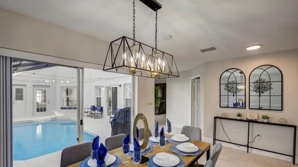 A dining area with a pool view, modern decor, and a large mirror. - Disney & Universal Studios Vacation Home (Kissimmee)