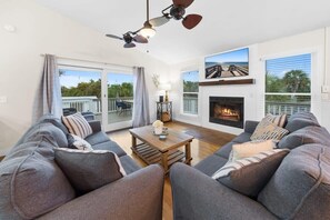 A modern living room with a fireplace, grey sofas, a wooden coffee table, and a ceiling fan.