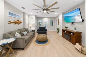 A living room with a ceiling fan, a television, a sofa, a coffee table, and a wooden cabinet.