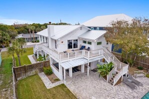 A two-story house with a covered patio, a staircase, and a pool.