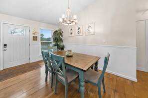 A dining area with a wooden table and teal chairs, a chandelier, and framed artwork on the wall. - Bid-A-Wee Beach Home-Private Pool (Panama City Beach)