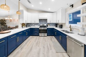 A modern kitchen with white and blue cabinets, stainless steel appliances, and a central island. - Bid-A-Wee Beach Home-Private Pool (Panama City Beach)
