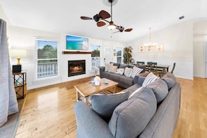 A living room with a fireplace, a sofa set, a dining table, and a ceiling fan. - Bid-A-Wee Beach Home-Private Pool (Panama City Beach)